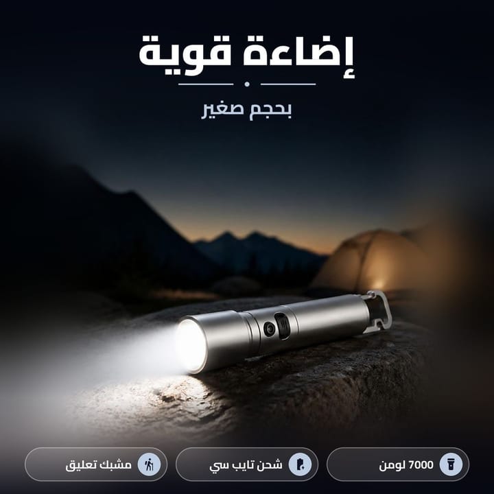 كشاف يدوي صغير فضي شاعل على صخرة قدام خيمة وجبال وقت الغروب